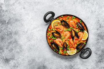 Traditional Spanish paella with seafood in a frying pan. Gray concrete grunge background. Top view, flat lay. Mediterranean Kitchen.