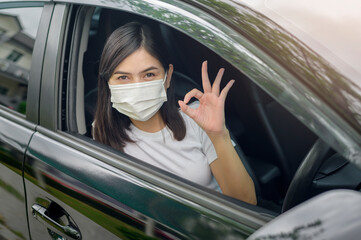 Young beautiful woman wearing a protective mask driving a car