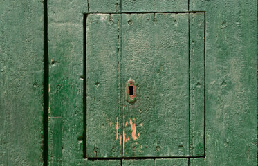 Holzklappe in einer grünen Tür mit Schlüsselloch