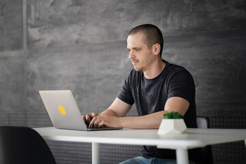 Happy man working on laptop in library or coworking office space