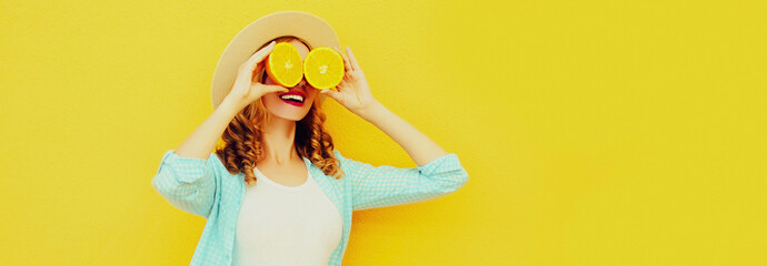 Summer portrait of happy smiling woman covering her eyes with slices of orange and looking for...