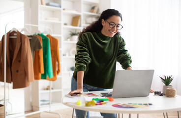 Happy Clothing Designer Woman Using Laptop Standing In Showroom
