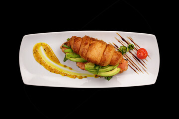 Croissant with salmon and avocado, isolate on black