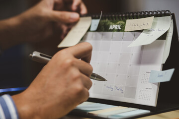 Close up of businessman checking memo and planning schedule on calendar planner.
