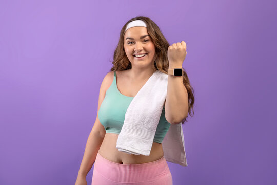 Glad young european plus size female in sportswear with towel show fit tracker after workout - Powered by Adobe