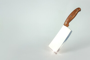 Kitchen knife balanced on its end. Sharp large kitchen knife on a gtey surface with sunlight.