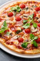 Sliced tasty pizza with mushroom, cheese, tomatoes, pepper, becon, sausage, fresh salad and pesto. Italian pizza