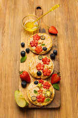 Sweet sandwiches peanut butter with fruits, berries with honey on a wooden board, top view. Banner Healthy tasty breakfast.