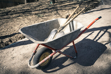old reliable working wheelbarrow with shovels on a construction site