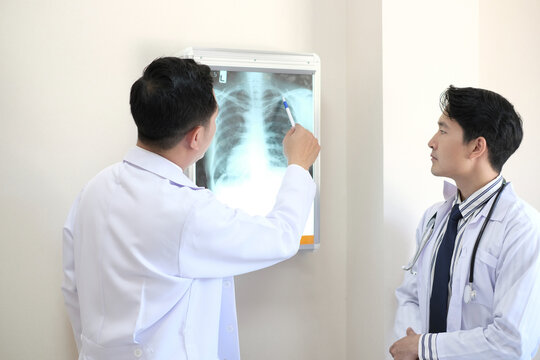 Concept of medical healthcare Male doctor examining patient chest x-ray film lungs scan at radiology department in hospital. Covid-19 xray test, covid worldwide virus epidemic spreading concept image.