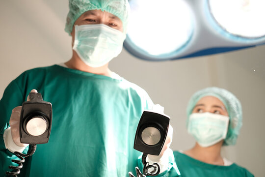 Concept of Doctors give resuscitation. Team of professional surgeons performing operation in hospital, they are holding defibrillator and help while patient will die operation room at hospital cpr.