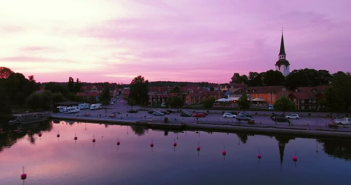 Aerial Shot Of Cross Symbol On Tall Church Against Cloudy Sky, Drone Flying Forward Towards Cars In Parking Lot At Sunset - Mariefred, Sweden