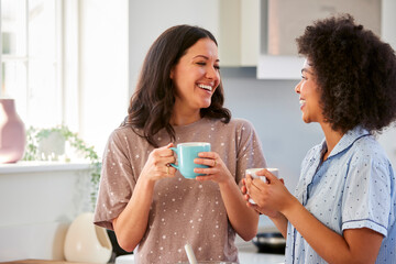 Loving Same Sex Female Couple Wearing Pyjamas Making Morning Pancakes In Kitchen At Home