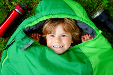 Preschool little girl in sleeping bag camping. Outdoors activity with children in summer. Fun and...