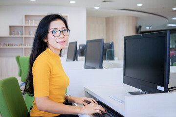 Female college student using a computer in library