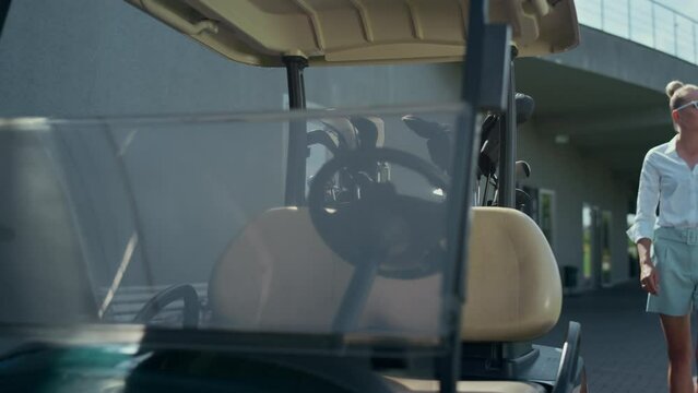 Woman sitting golf cart on sunny day. Professional player start engine on course
