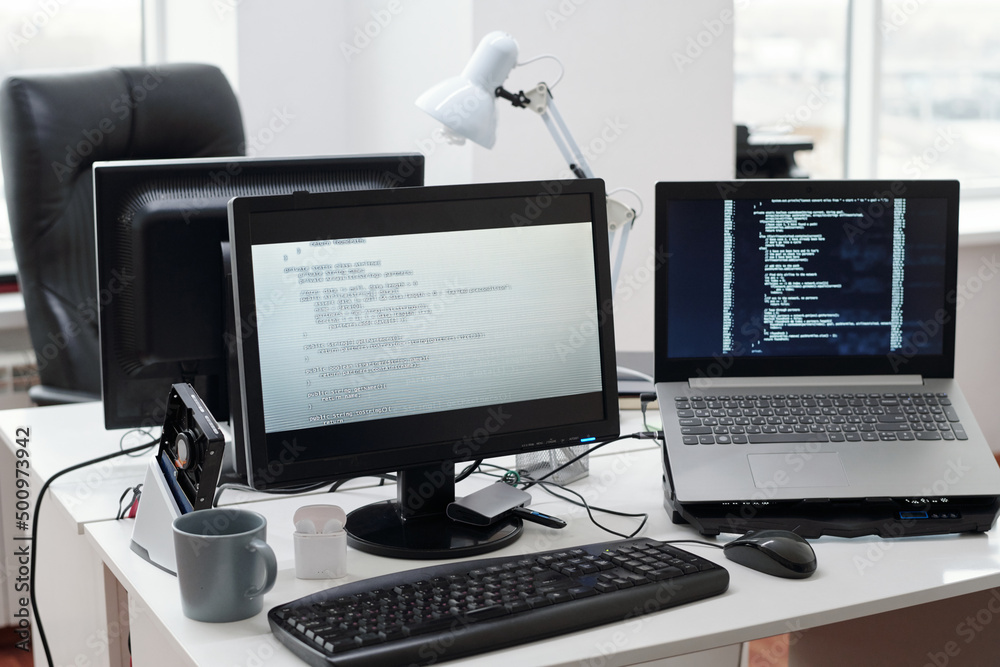 Poster Decoded data on computer and laptop screens standing on workplace of contemporary programmer in large openspace office