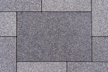 A large gray rectangular stone in the center. Surrounded by small rectangular stones. Can be used as background, wall or floor. Empty area for text.