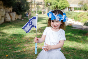 A little girl in a blue and white wreath (Symbol of the Israeli flag) plays in the garden