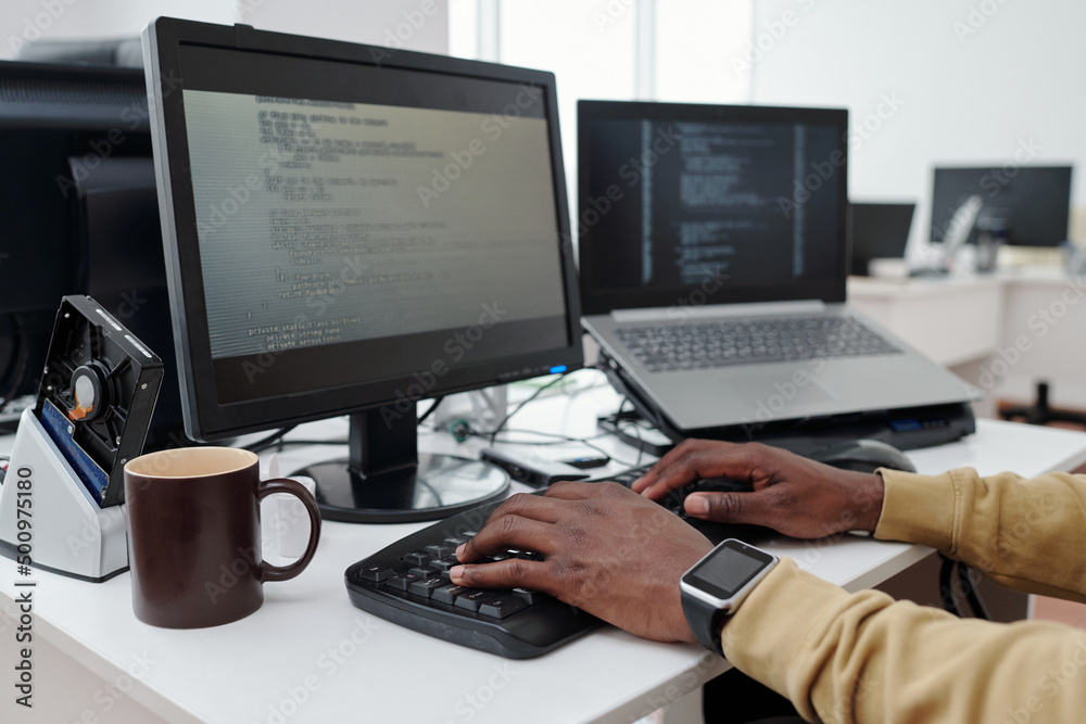 Poster Hands of young male programmer or it-engineer decoding data on computer screen while pressing buttons of keyboard in office