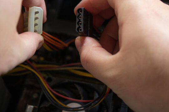 Man hand holding a molex male and female ends of sockets and connecting them into one piece to make computer work again.(selective focus)