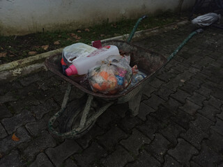A wheelbarrow cart full with trashes and a white fluid. Garbage disposal.