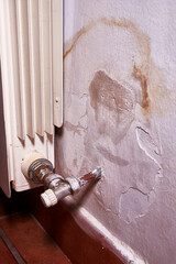 Moisture on the wall next to a heating radiator. Vertical photo.