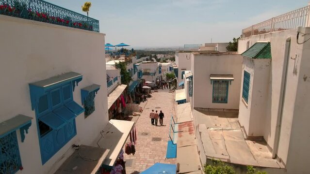 Aerial Forward Shot Of Tourists Exploring Residential Town On Sunny Day - Djerba, Tunisia