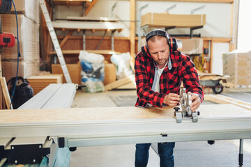 A carpenter works in his workshop with the large sliding table saw
