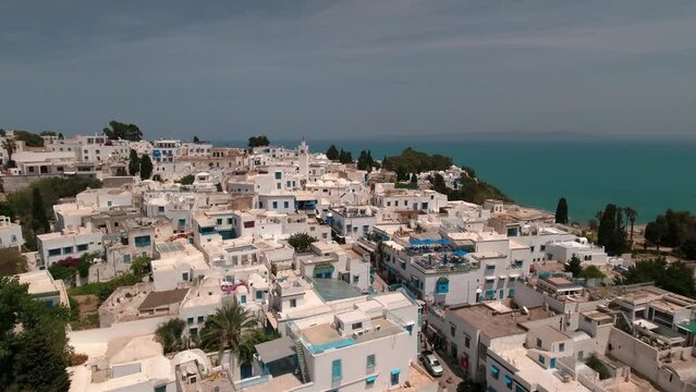 Aerial Forward Shot Of White Residential Buildings And Mosque In Town On Hill By Sea - Djerba, Tunisia