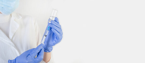 Female doctor in a protective blue suit with a syringe on a white background with copy space