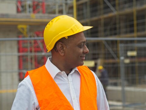 Profile portrait of a smiling civil engineer or factory worker wearing a safety helmet and looking aside