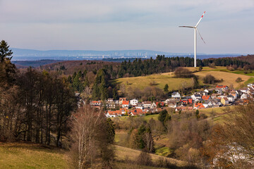 A single wind turbine on a hill above a village