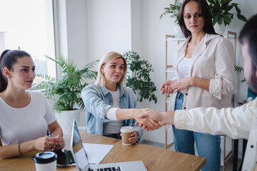 Man and woman shaking hands to each other while making deal in office
