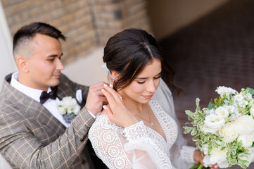 Above view of thoughtful bridegroom in vogue suit, making  wedding gift for bride and tying jewelry...