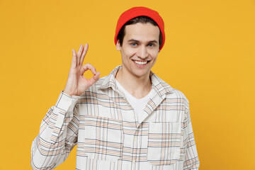 Young smiling happy satisfied cool fun cheerful man 20s wearing white casual shirt orange hat show ok okay gesture isolated on plain yellow color background studio portrait. People lifestyle concept.