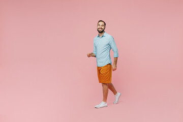 Fototapeta na wymiar Full body young smiling happy fun cheerful caucasian man 20s wear classic blue shirt walking going look camera isolated on plain pastel light pink background studio portrait. People lifestyle concept.