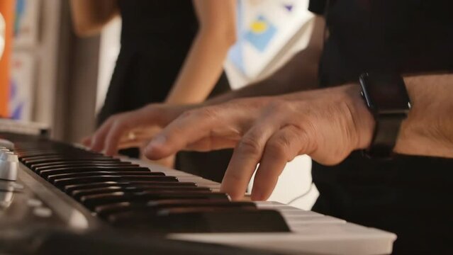 restaurant musicians in the process of performing a song. Male fingers play the synthesizer next to a singing woman. slow motion