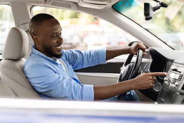 Smiling black man driving new car in city