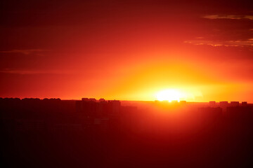 Sunset on a red sky with evening clouds in the city. The setting evening sun over the city with high-rise buildings