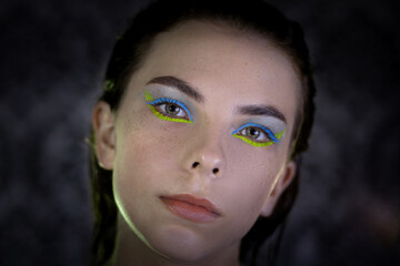 Fototapeta premium portrait of a Ukrainian girl in the dark with make-up in the colors of the Ukrainian flag