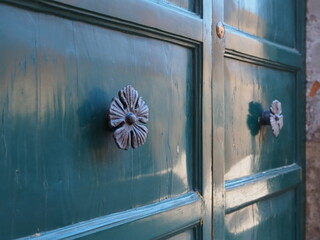Green wooden door with flower-shaped handles.