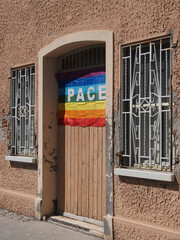 Building facade, on the wooden door there is a rainbow flag.