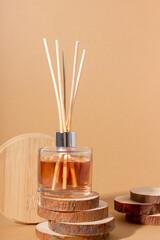 reed diffuser bottle on the podium. Incense sticks for the home with a floral scent with hard shadows. The concept of eco-friendly fragrance for the home - obrazy, fototapety, plakaty