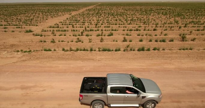 Aerial Shot Of People Driving Pull Up Truck In Agricultural Field On Sunny Day - Djerba, Tunisia