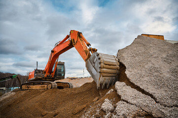 Excavator digs soil with bucket at construction site