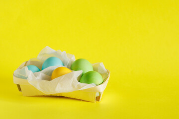 Easter eggs in a basket on a bright yellow background.