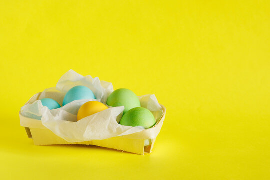 Easter eggs in a basket on a bright yellow background.
