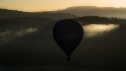 Hot-air balloon rising at sunrise in a Dordogne valley