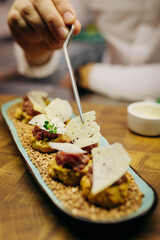 Chief chef serving snacks, canapes or sandviches adding finishing touch on dish before it is going to be served for restaurant guests